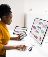 Woman looking at a computer screen and mobile devices.